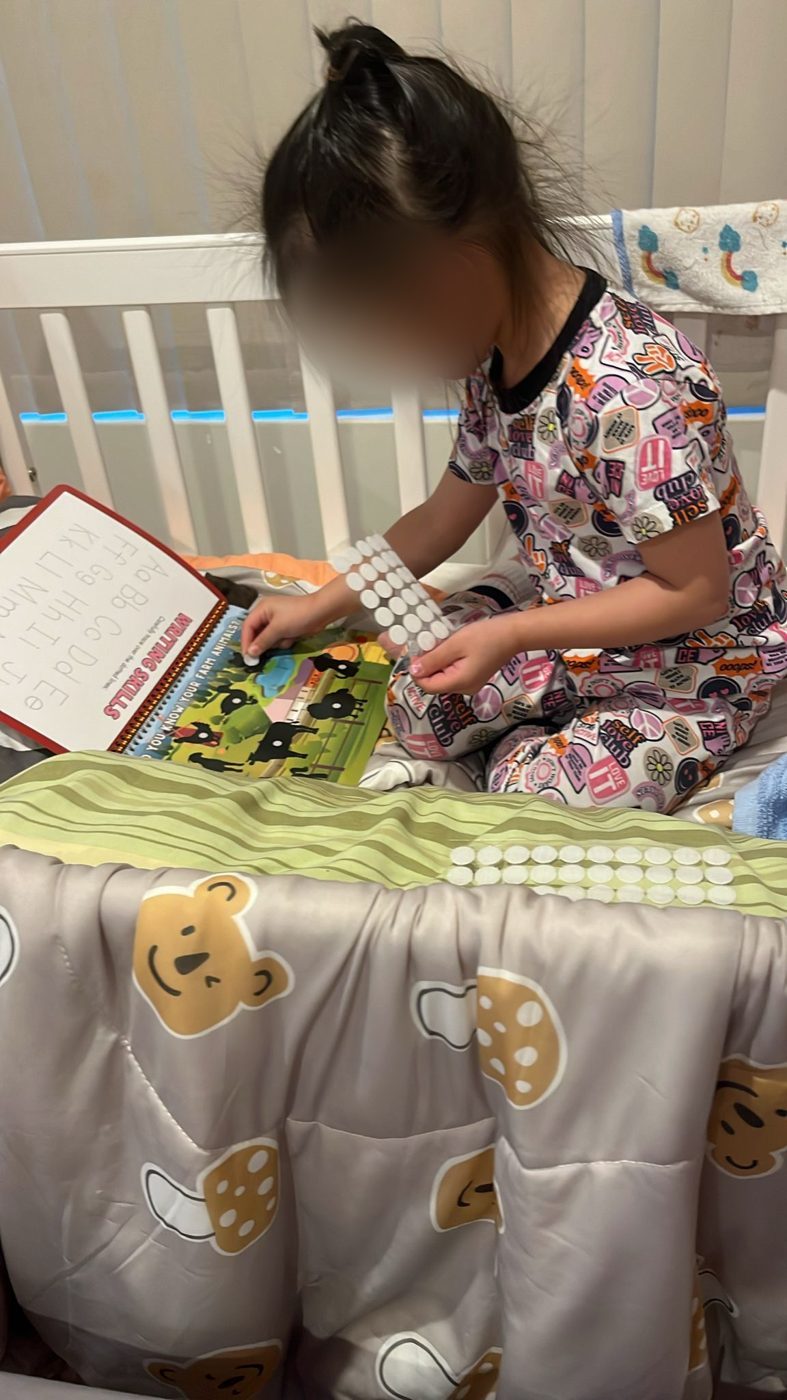 Child playing with the busy book on a bed
